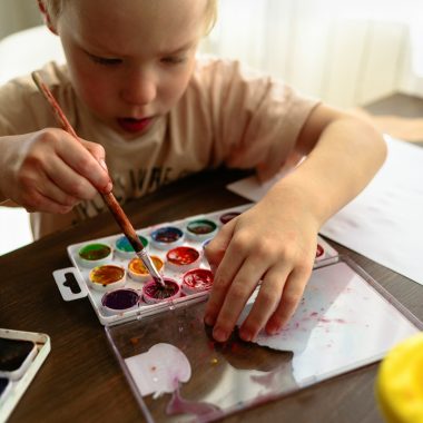 Child drawing in watercolor very enthusiastically